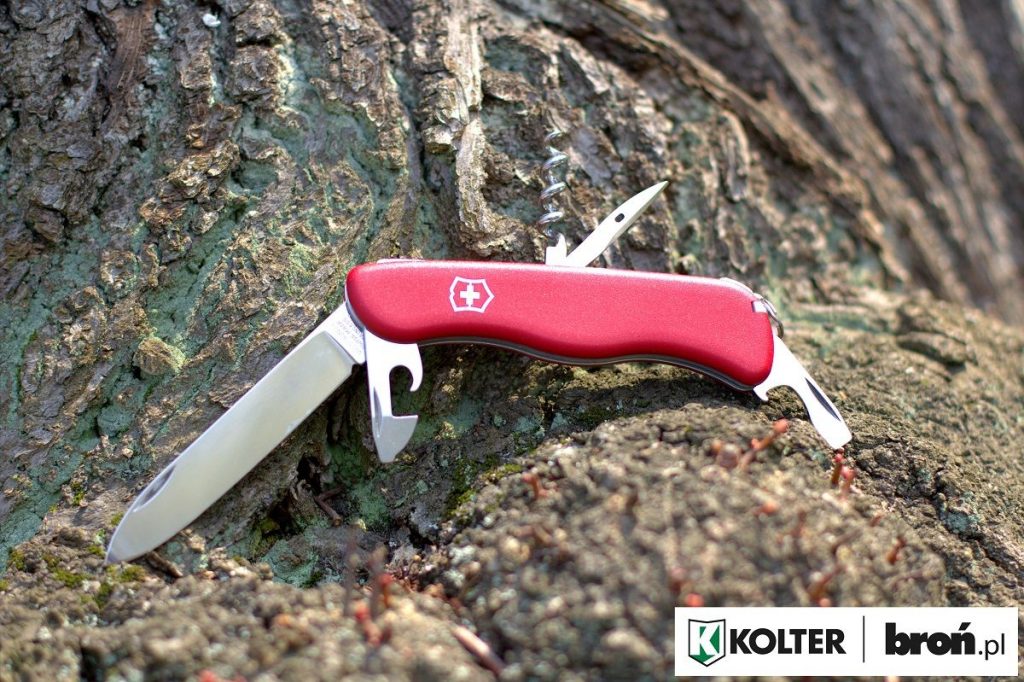 Victorinox PICKNICKER con cachas rojas sobre tronco de madera con las funciones abiertas