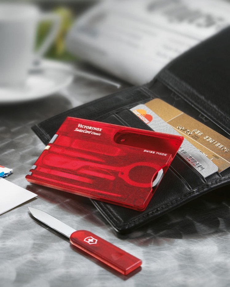 Victorinox Swiss Card encima de cartera para comparar tamaño. Es del mismo tamaño que una tarjeta de crédito o débito