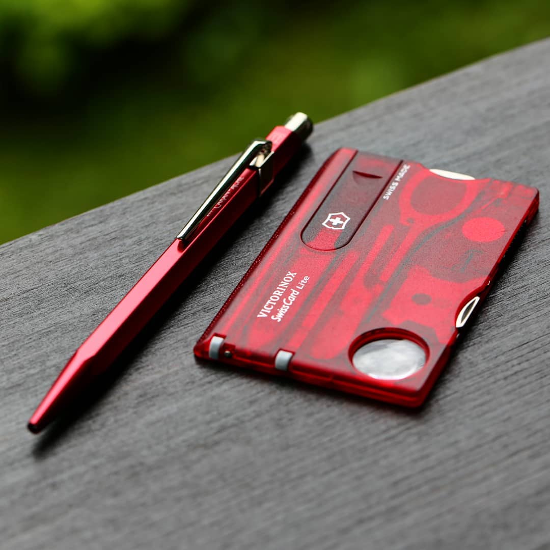 Victorinox Swiss Card Lite en una mesa acompañada de un bolígrafo también en color rojo